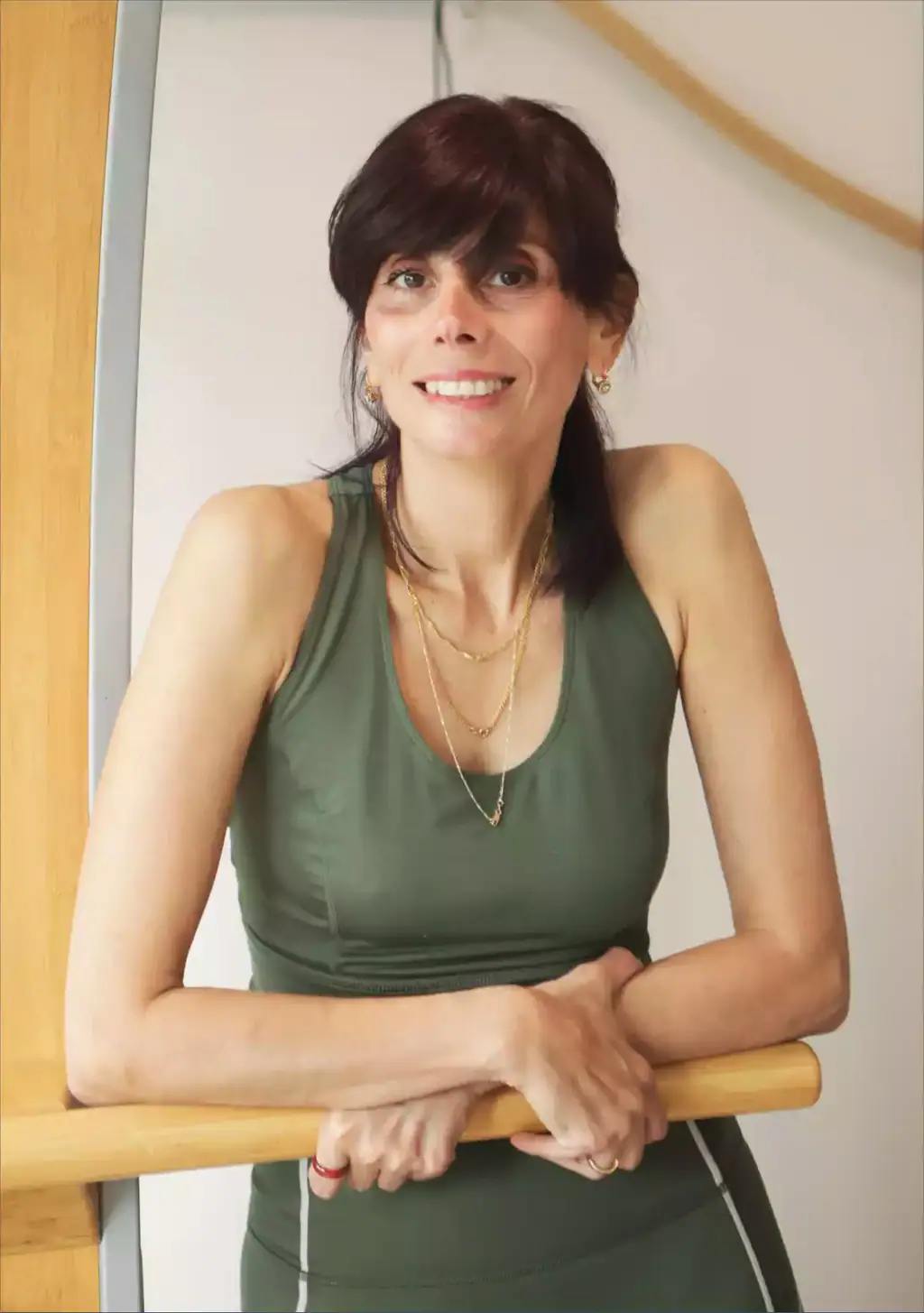 Arpi smiling, leaning on a wooden barre in her studio