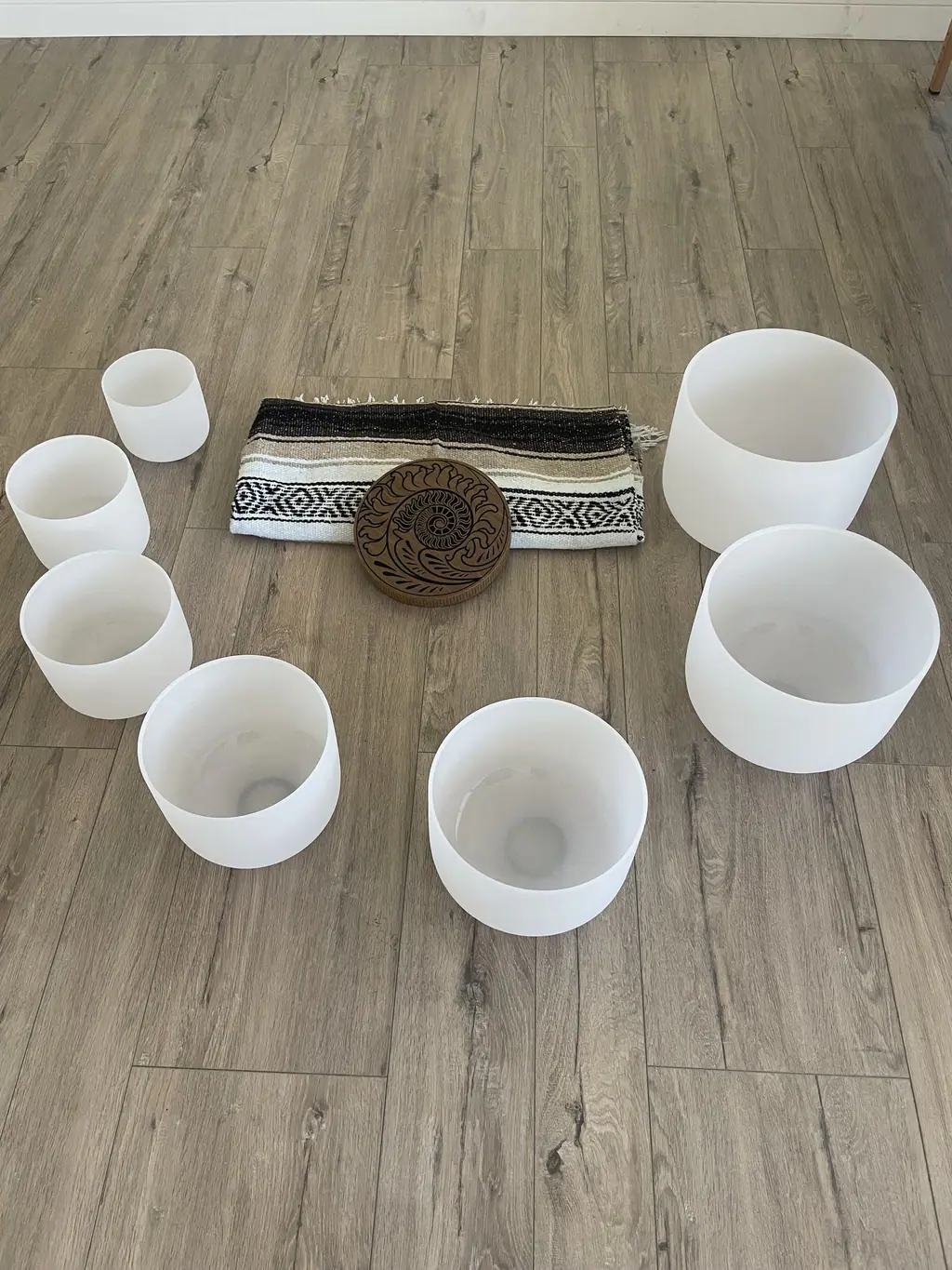 Crystal singing bowls arranged in a circle on a wooden floor